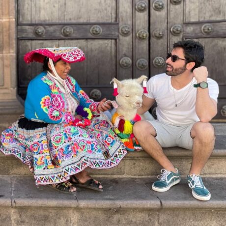 Mulher com roupa típica andina do Peru, uma lhama decorada e home em roupas ocidentais